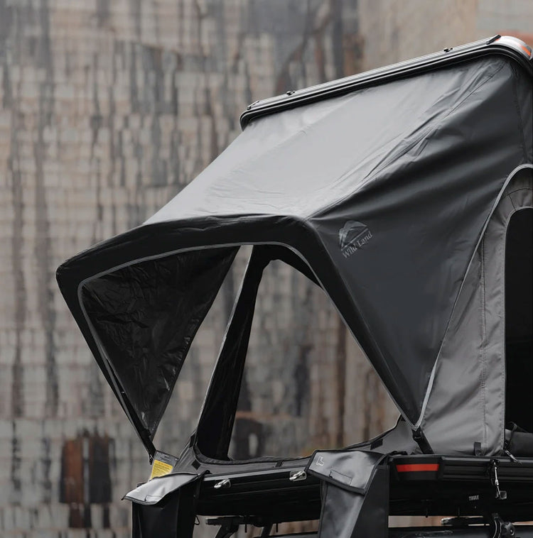Black and gray awning attached to a vehicle with a blurred cityscape background