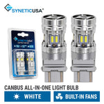 Two silver SyneticUSA canbus all-in-one LED 3157 3157CK light bulbs shown next to their blue retail blister packaging, with text indicating they are white and built-in fans.