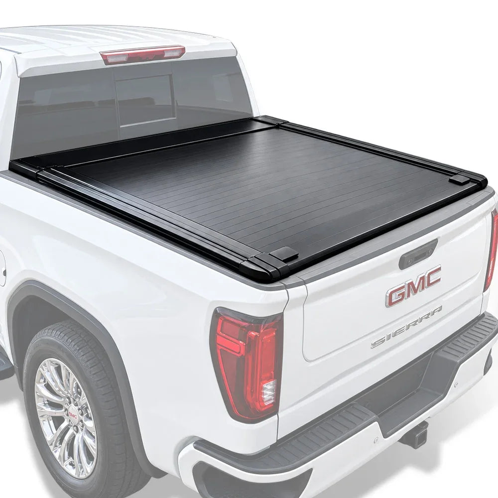 A black truck bed cover installed on the bed of a white GMC Sierra pickup truck, shown from a rear three-quarter angle against a clean white background.