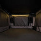 Dark interior of a vehicle with a lit strip light, possibly inside a camper or truck bed.