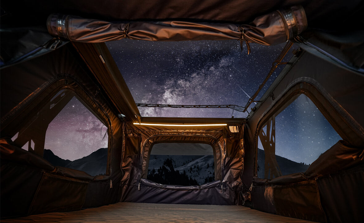 Starry night sky viewed from inside a tent with mountains in the background