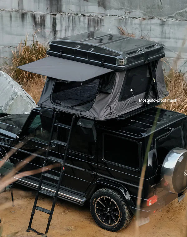 Black SUV with a rooftop tent and ladder against a rocky background