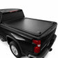 A black roll-up truck bed cover installed on the bed of a black pickup truck, shown from a rear three-quarter angle against a white studio background.