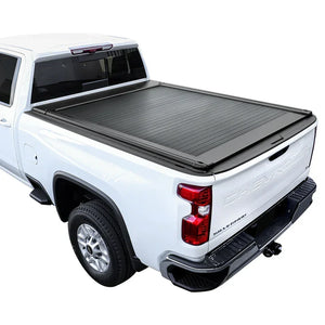 A black retractable tonneau cover installed on a white Chevrolet Silverado pickup truck.