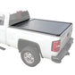 A retractable tonneau cover made of aluminum and plastic, installed on the bed of a white pickup truck.