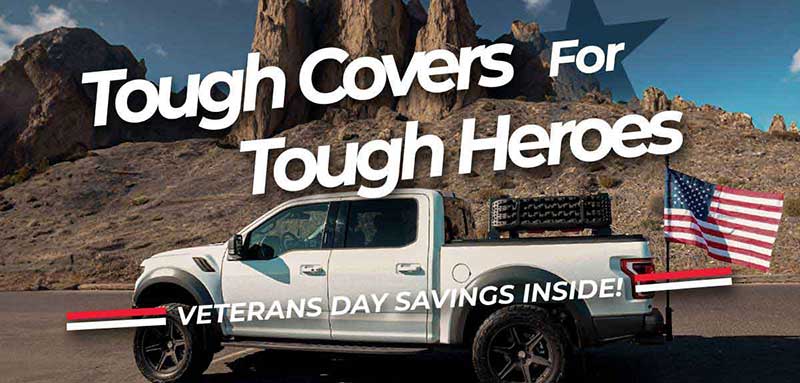 Truck with American flag in a desert landscape with text 'Tough Covers For Tough Heroes' and 'Veterans Day Savings Inside!'.