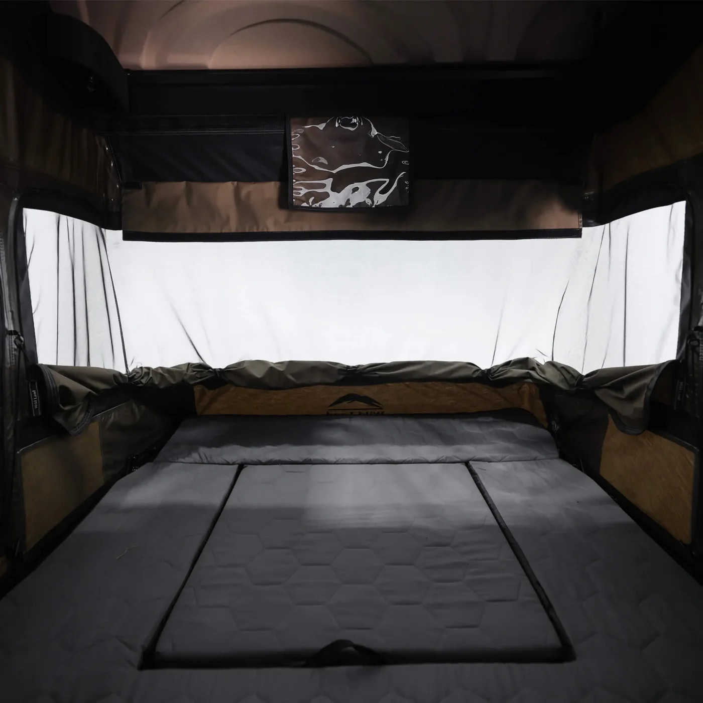 Bed inside a vehicle with a canopy and window in the background