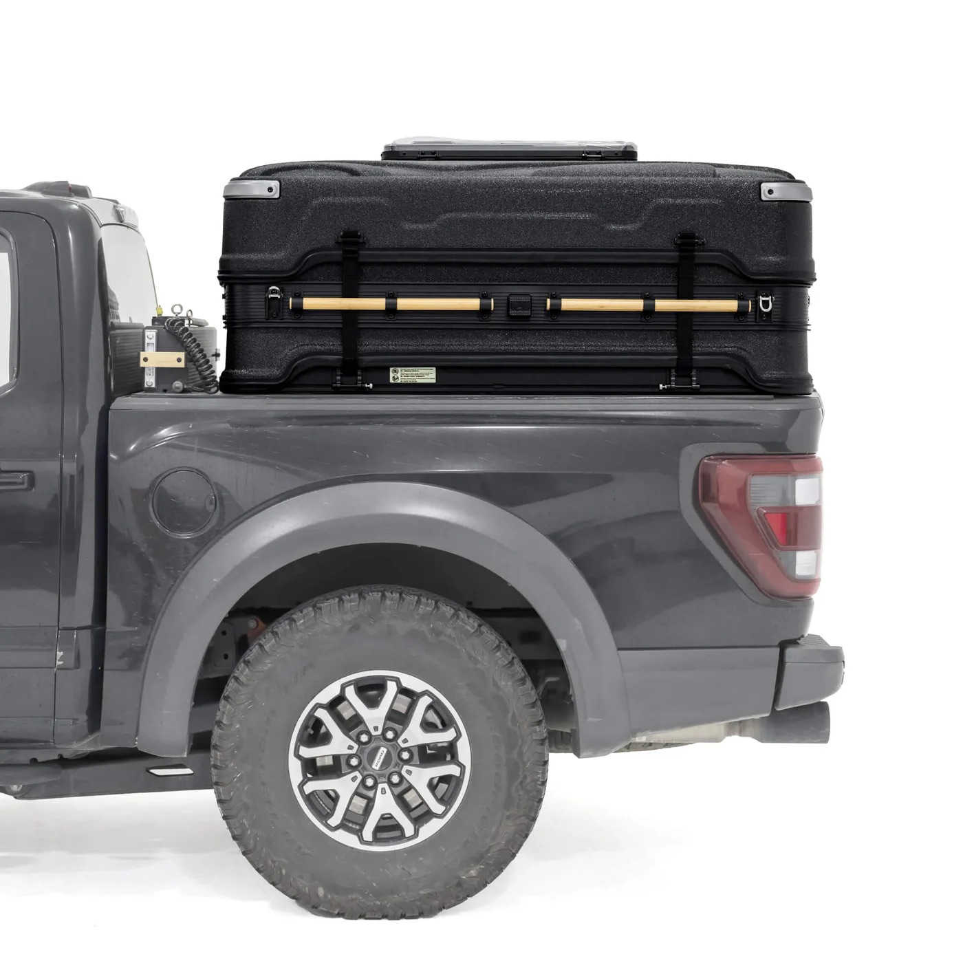 Black roof box on a gray truck bed with a white background