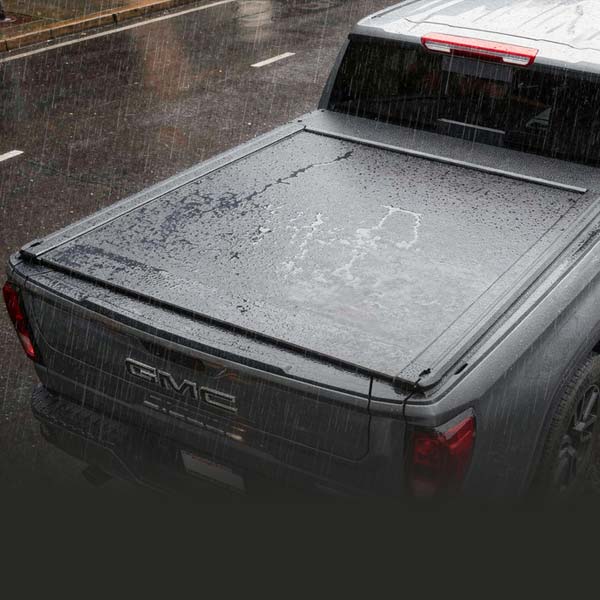 GMC truck bed with a tonneau cover on a rainy day