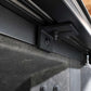 Close-up of a black metal mounting bracket attached to a dark gray textured panel, with a bolt and screw visible.
