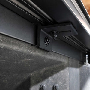 Close-up of a black metal mounting bracket attached to a dark gray textured panel, with a bolt and screw visible.