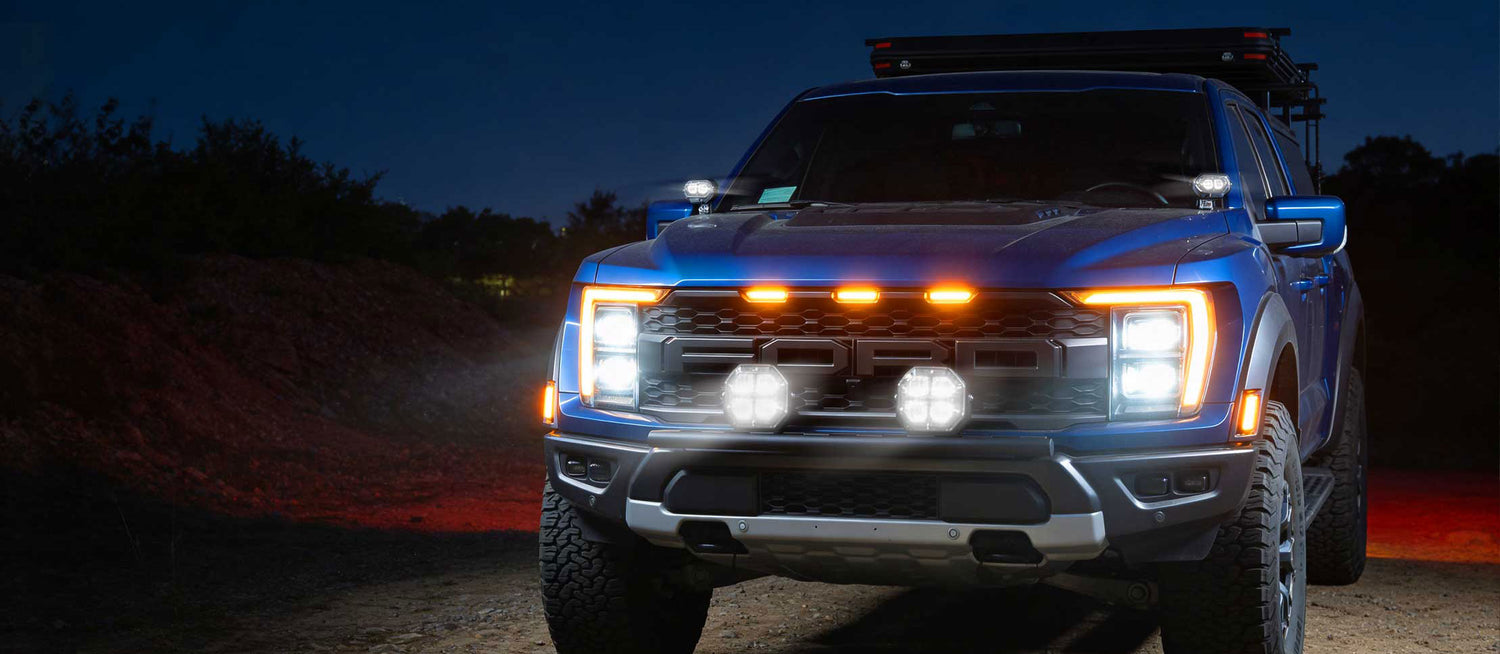 Blue pickup truck with illuminated headlights on a dark road