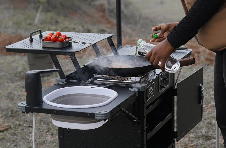Portable camping stove with a frying pan and tomatoes outdoors