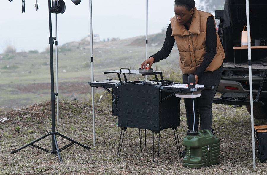 Person setting up a portable camping stove outdoors with a scenic background