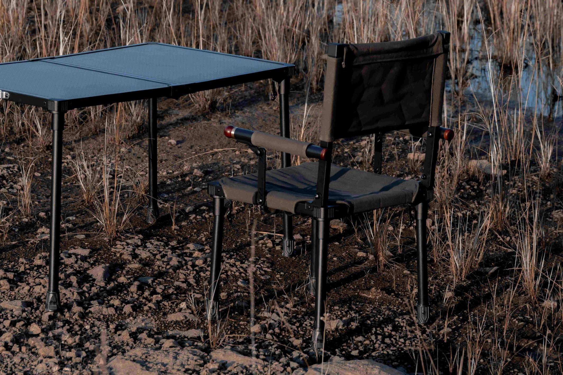 mts-c camping table and chair set in a natural outdoor setting with dry grass and earthy tones.