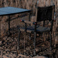 mts-c camping table and chair set in a natural outdoor setting with dry grass and earthy tones.