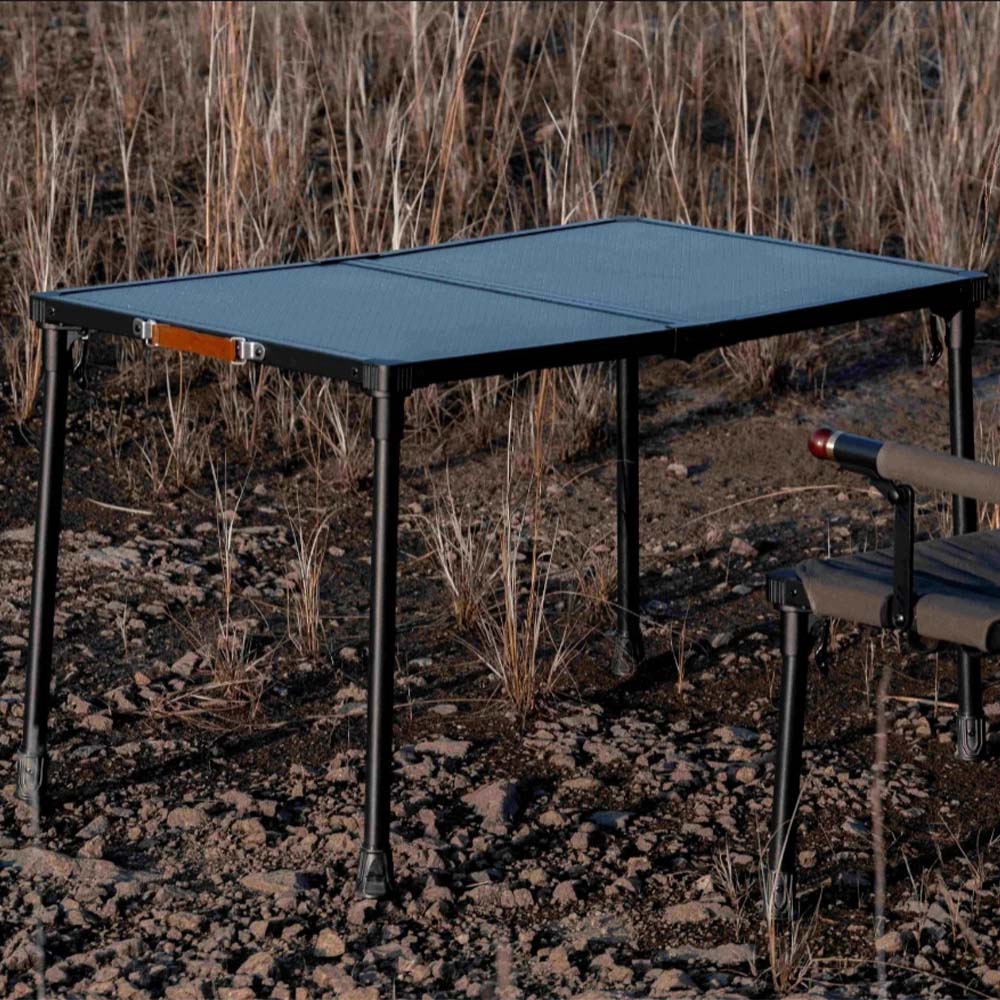 Wild Land MTS-C foldable aluminum camping table set up outdoors on rocky ground.
