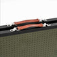 Close-up of a black metal tool case with olive green perforated sides and brown leather handles secured by silver metal clips.
