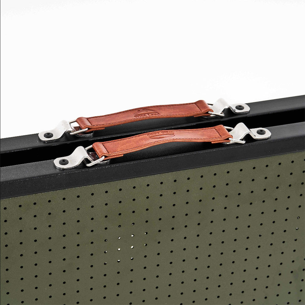 Close-up of a black metal tool case with olive green perforated sides and brown leather handles secured by silver metal clips.