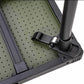 Close-up detail of a folding table showing a black metal leg clamp attached to a perforated olive green tabletop, on a white background.