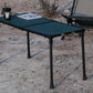 Camping chair and table set up outdoors near a body of water.