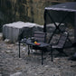 Camping setup with a table and chairs by a body of water.
