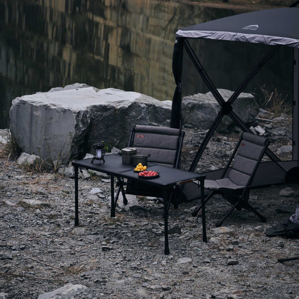 Camping setup with a table and chairs by a body of water.