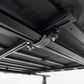 Close-up of a black retractable tent or canopy mounted on a metal frame, showing the track system, bracket, and attachment hardware.