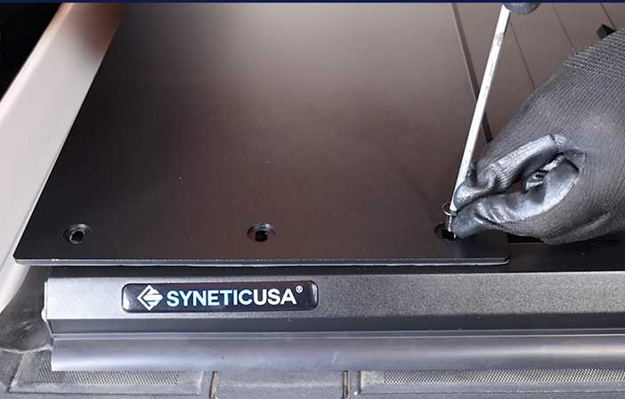 Person using a tool on a SYNETICUSA branded metal surface