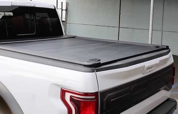White truck with a black tonneau cover in an indoor setting