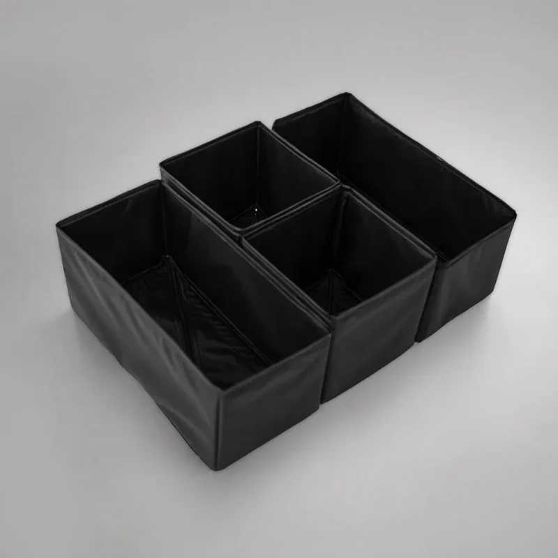 Four black fabric storage bins arranged in a two-by-two grid on a light gray studio background.
