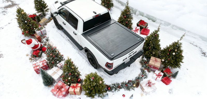 White truck with a tonneau cover in a snowy landscape with Christmas trees and presents.