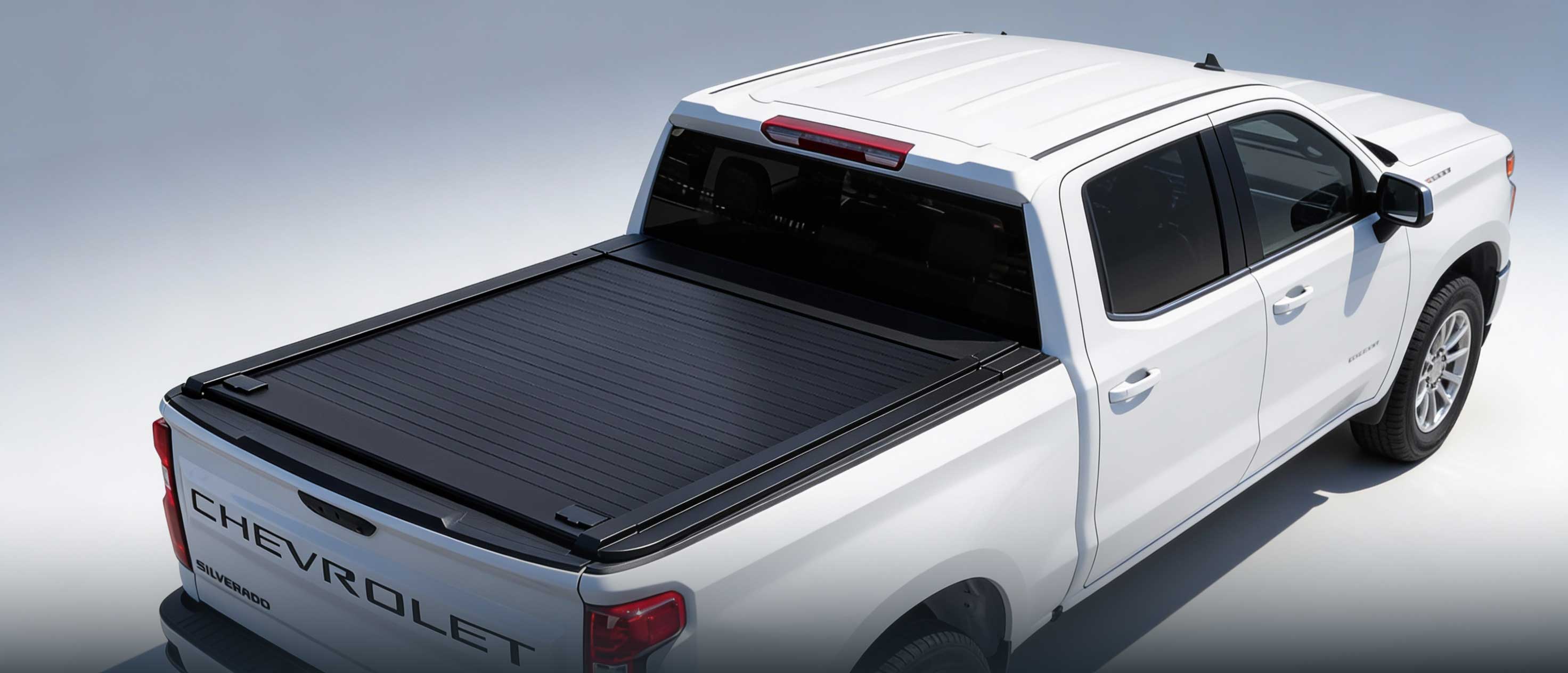 White Chevrolet truck with a black tonneau cover on a light gray background