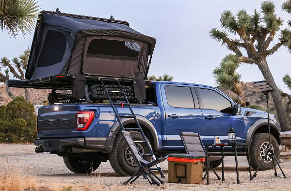 Blue truck with a rooftop tent in a desert setting
